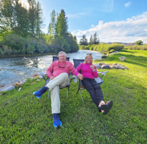 Couple relaxing by river on sunny day.